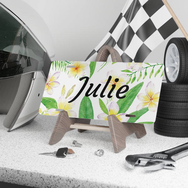 Plumeria Personalized Custom Front License Plate sitting on a shelf 