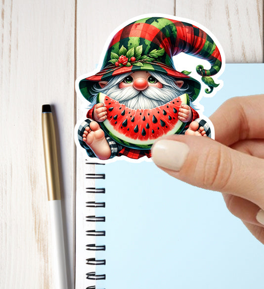 Gnome sticker with a watermelon held by a hand above a notebook