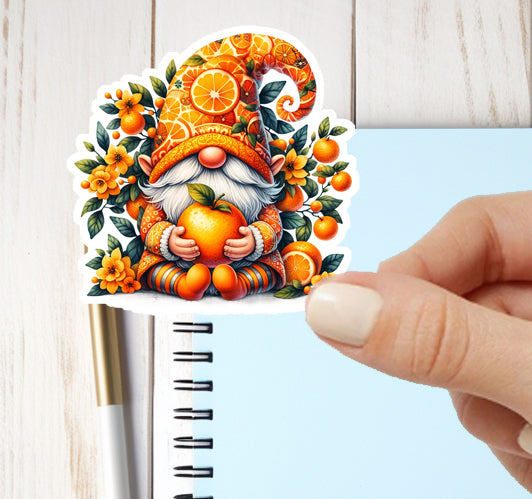 Decorative sticker of a gnome with oranges held by a hand over a notebook