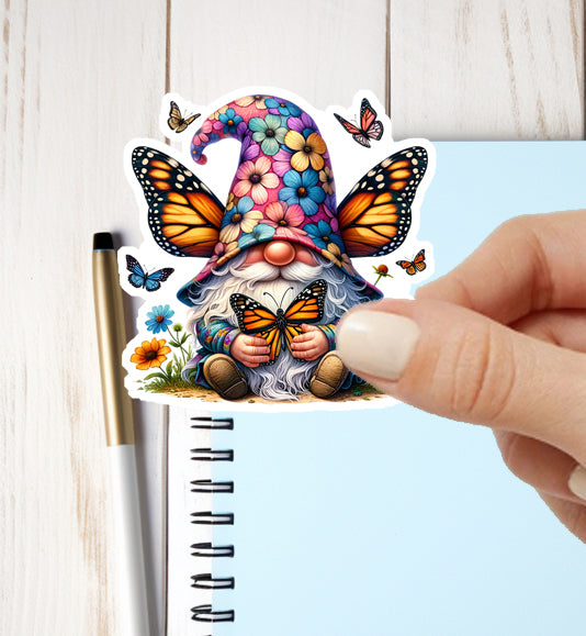 Colorful gnome sticker with butterflies held over a notebook