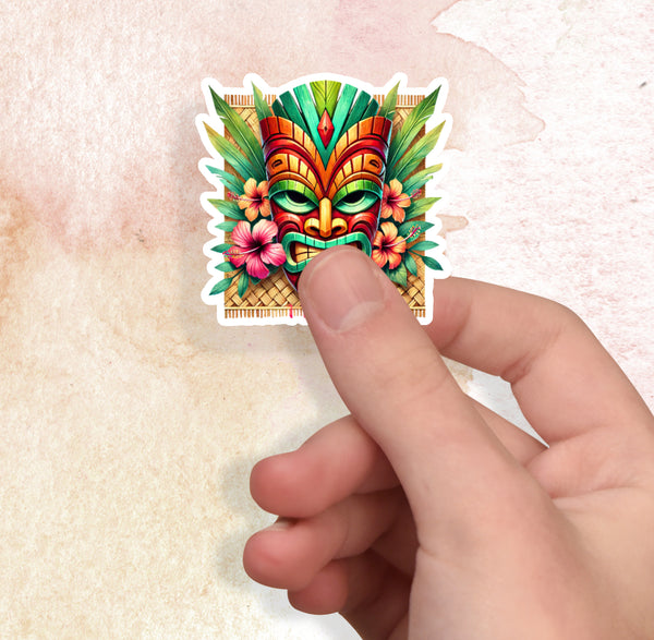 Colorful tiki mask sticker held by a hand on a textured beige background