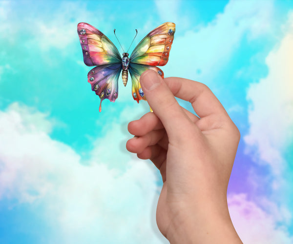 Hand holding a colorful butterfly against a pastel sky background