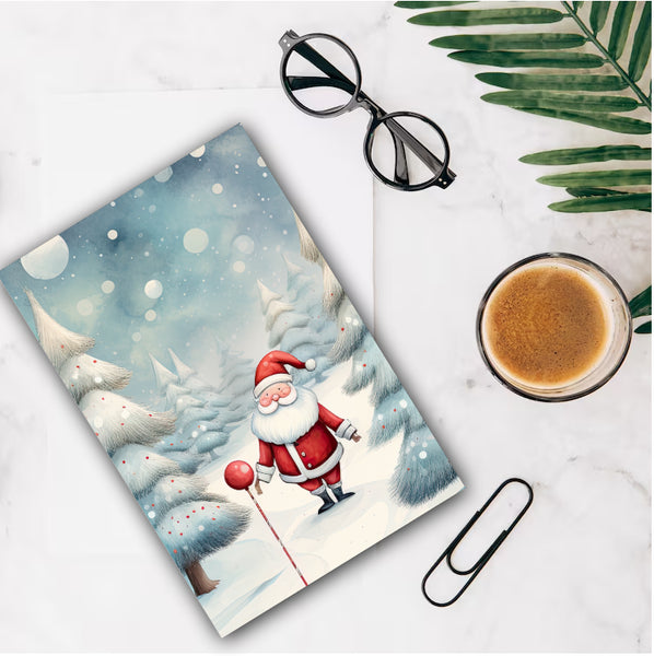 Notebook with Santa Claus illustration on a white surface with a cup of coffee and glasses.