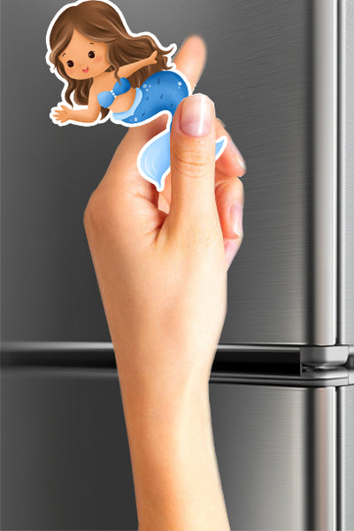 Hand holding a cartoon character magnet in front of a refrigerator.