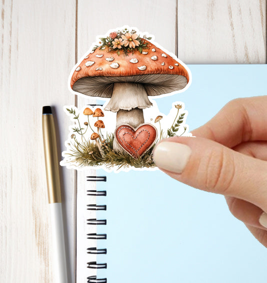 Decorative mushroom sticker with a heart held over a notebook