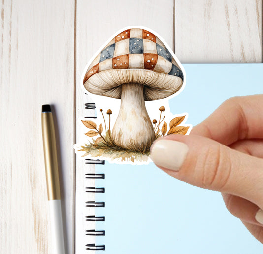 Mushroom-shaped sticker being placed on a notebook with a pen next to it.