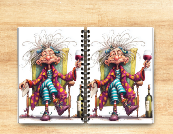 A spiral-bound notebook lying open on a light wood surface, showing a whimsical cartoon illustration of a woman with wild white hair sitting in a yellow chair and holding a glass of red wine.
