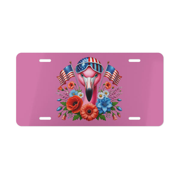 Pink license plate with a flamingo wearing sunglasses and American flags, surrounded by flowers on a white background.