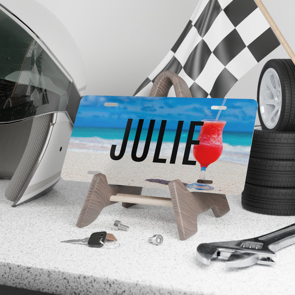 Personalized license plate with 'JULIE' and a drink design, surrounded by car parts and tools.