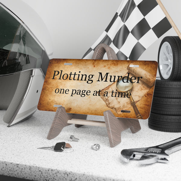 License plate with 'Plotting Murder one page at a time' text, surrounded by car parts and tools.