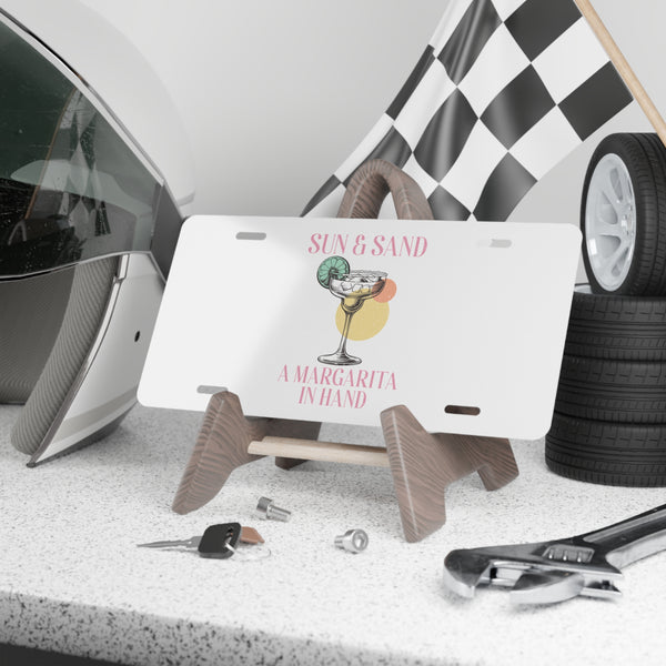 License plate with a cocktail design on a stand, surrounded by car parts and tools.