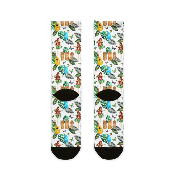 Pair of socks with a tropical pattern featuring hula dancers, ukuleles, and leaves on a white background.