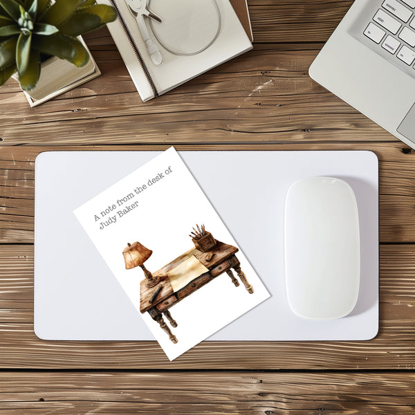 Note card with illustration of a desk and lamp on a mouse pad with a computer mouse, on a wooden desk.