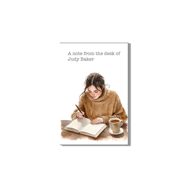 Book cover with illustration of a woman writing and a cup of coffee, titled 'A note from the desk of Judy Baker'.