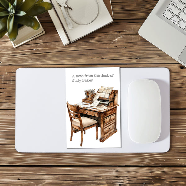 Mouse pad with a desk illustration and text on a wooden desk with a laptop and plant.